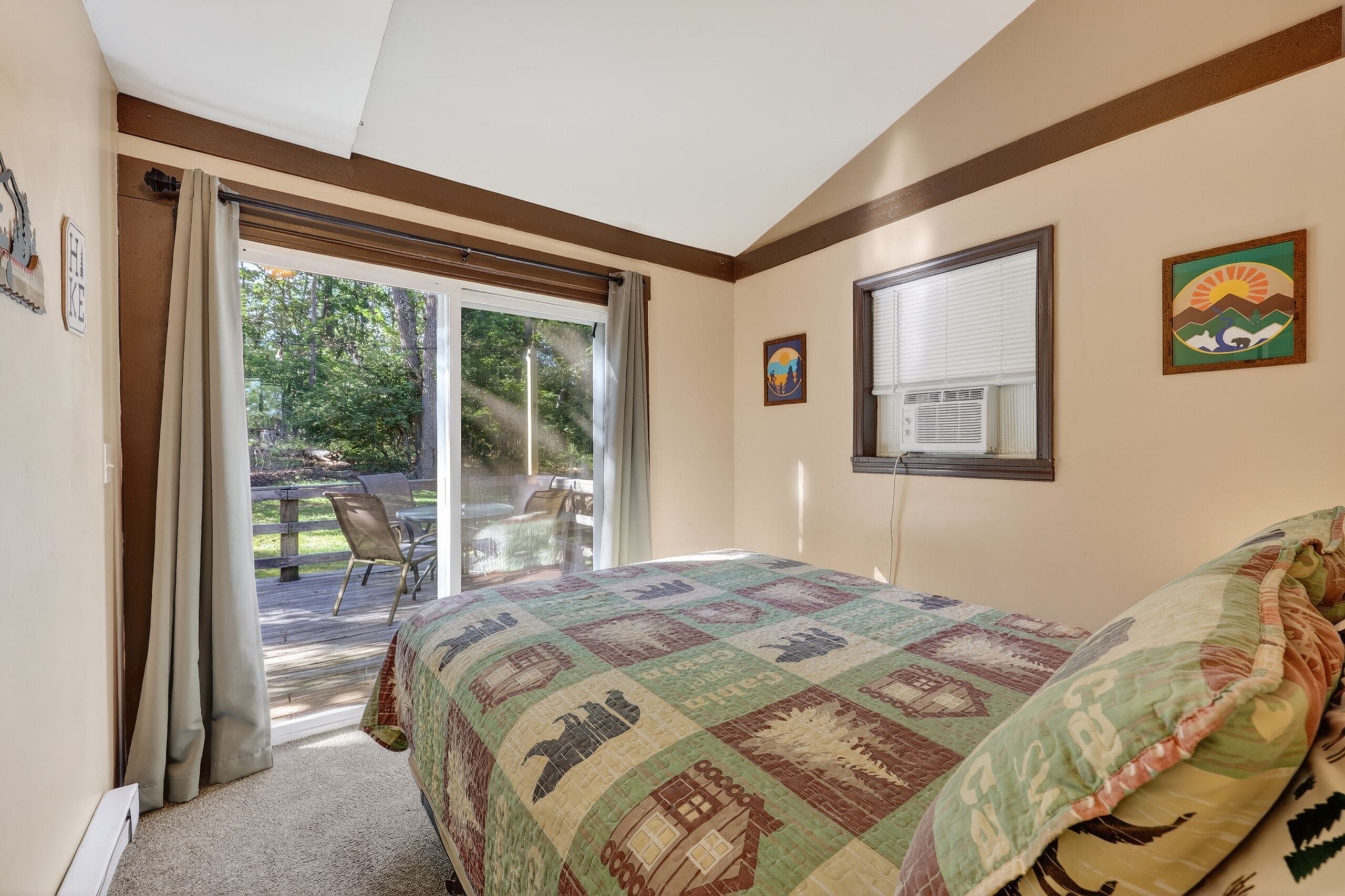 A bedroom with a large bed, a sliding glass door to a patio, and a window with blinds.