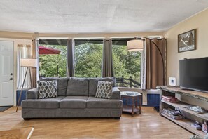 A living room with a grey sofa, a TV, and a bookshelf with board games. - Luray retreat - Hiking and Shenandoah River nearby - Dog friendly (Page County)