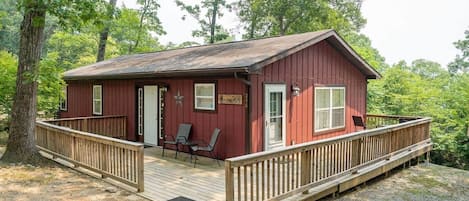 A red cabin with a deck, two chairs, and a small table.