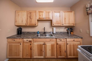 A kitchen with wooden cabinets, a granite countertop, a sink, and a stove. - Treetop Hideaway / Stunning Views / Dog friendly (Page County)