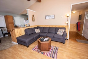 A living room with a sectional sofa, a wooden coffee table, and a kitchen in the background. - Scenic Views / Hike, kayak nearby / Dog friendly (Page County)
