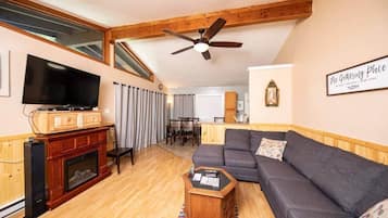 Un salon avec une cheminée, un téléviseur, un canapé et un ventilateur de plafond.