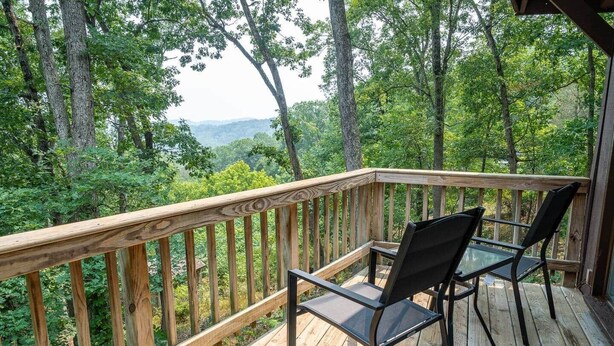 A wooden deck with a glass table and chairs, surrounded by trees and a view of the landscape. - Scenic Views / Hike, kayak nearby / Dog friendly (Page County)