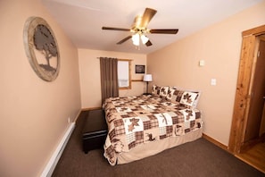 A bedroom with a bed, a ceiling fan, a window with curtains, a wall-mounted air conditioner, and a door. - Scenic Views / Hike, kayak nearby / Dog friendly (Page County)
