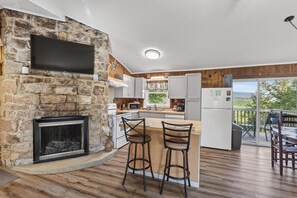 Una cocina moderna con una pared de piedra, una chimenea y una barra con taburetes.