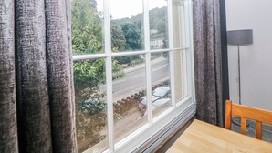 Ein Zimmer mit einem großen Fenster, einem Holztisch und einem Stuhl.