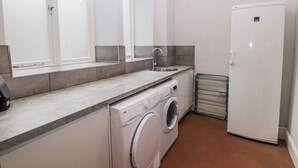 Eine kleine Küche mit Waschmaschine, Spüle und Kühlschrank.