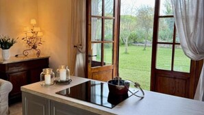 A kitchen with a built-in stove, a window with curtains, and a view of the outdoors.