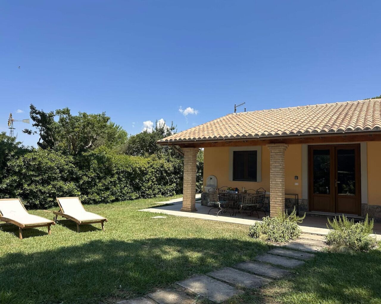 A house with a tiled roof, a covered patio, and two lounge chairs.