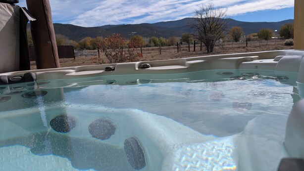 Un bain à remous avec vue sur les montagnes, entouré d’une terrasse en bois.
