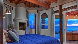 Ein Schlafzimmer mit einem großen Bett, einem Kamin und Meerblick.