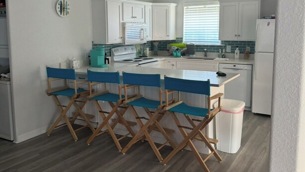 A modern kitchen with white cabinets, a blue countertop, and a wooden floor. - 2-bedroom house in peaceful Surfside Beach and beautiful view of the gulf (Surfside Beach)