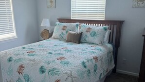 A bedroom with a bed, a ceiling fan, a nightstand, a lamp, and a wall sign. - 2-bedroom house in peaceful Surfside Beach and beautiful view of the gulf (Surfside Beach)