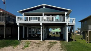 A two-story building with a covered porch and a flagpole. - 2-bedroom house in peaceful Surfside Beach and beautiful view of the gulf (Surfside Beach)