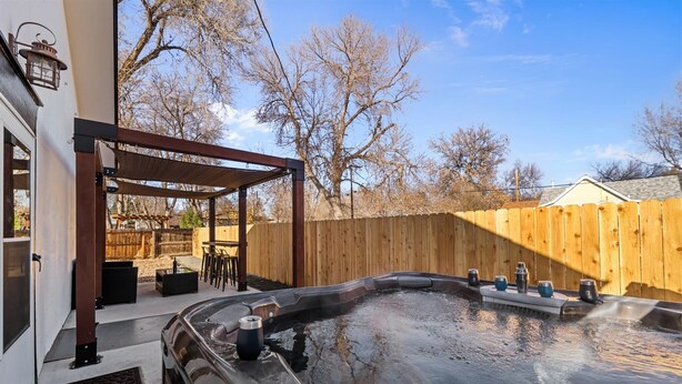 Ein Whirlpoolbereich mit Pergola, Holzzaun und Sitzgelegenheit im Freien.
