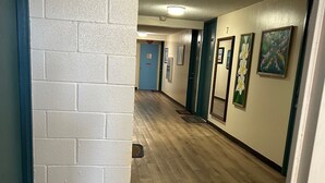 Ein Flur mit Fußmatte, einer Tür mit der Aufschrift 'EXIT' und einer Wand mit gerahmten Kunstwerken.