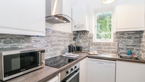 A compact kitchen with a microwave, toaster, kettle, and a small sink. - High Tor (Matlock)
