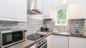 A modern kitchen with a microwave, toaster, kettle, and sink. - Riber (Matlock)