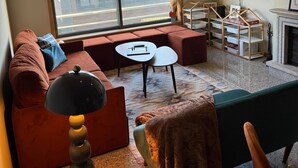 Un salon moderne comprenant un canapé, une petite table, une lampe, une cheminée et une grande fenêtre donnant sur un bâtiment à l’extérieur.