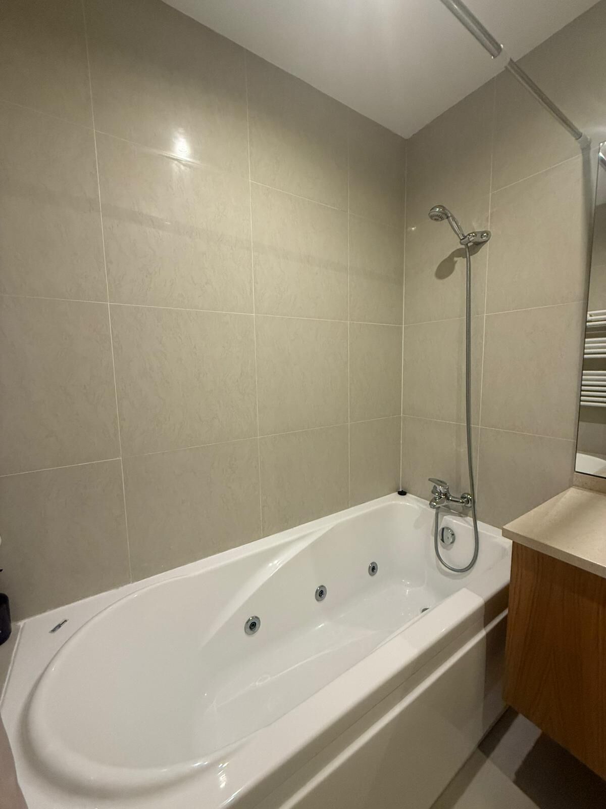 Une salle de bain moderne avec une baignoire sur pieds, une douchette et un meuble-lavabo avec un miroir.