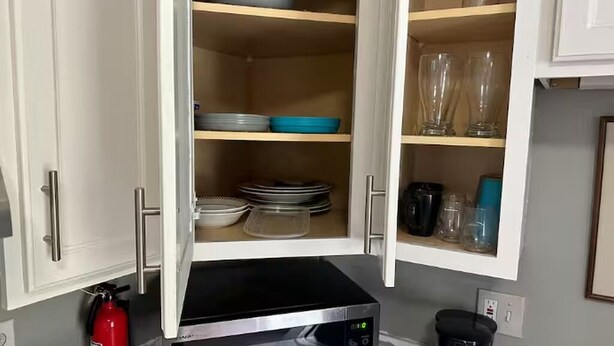 A kitchen with a microwave, a coffee maker, and shelves with dishes and glasses. - Relax. Breathe. Enjoy. (Berea)