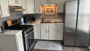A kitchen with white cabinets, a stainless steel refrigerator, a microwave, a stove, and a sink. - Relax. Breathe. Enjoy. (Berea)