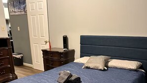 Un dormitorio con una cama grande, un tocador, una mesita de noche y una puerta.