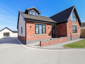 A two-story house with a brick facade, a pitched roof, and a garage. - 1 Talbot Drive (Holywell)