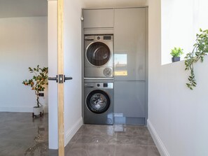 A laundry room with two stacked washing machines, a wooden door, and a potted plant. - 1 Talbot Drive (Holywell)