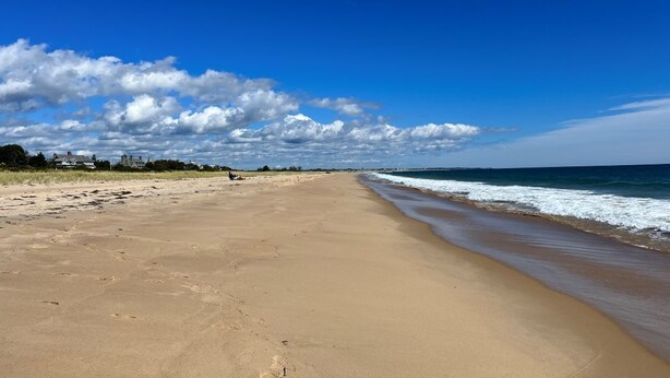 A wide sandy beach with a clear sky and ocean waves. - Large, 4,300 sq. ft. custom built 5 BR home on private 2.2 acres in Watch Hill (Westerly)
