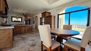 A spacious kitchen with a large island, wooden cabinets, and a dining area with a round table and chairs.