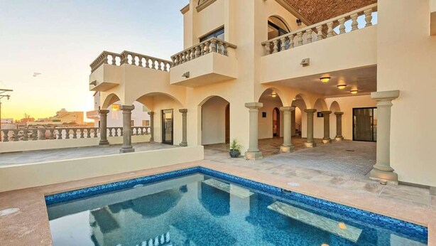 A hotel with a pool, multiple balconies, and a courtyard with columns.