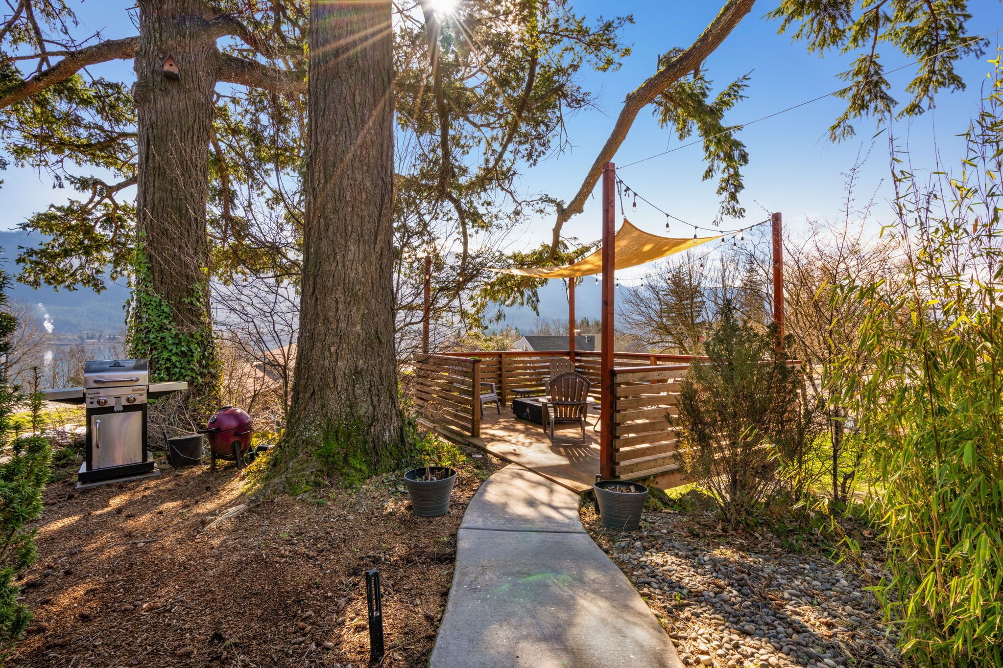 A covered outdoor area with a wooden deck, barbecue grill, and seating.