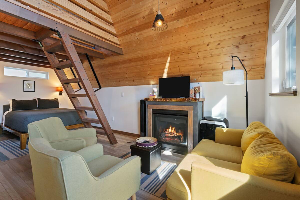 Un espacio tipo loft con chimenea, cama y zonas de estar.