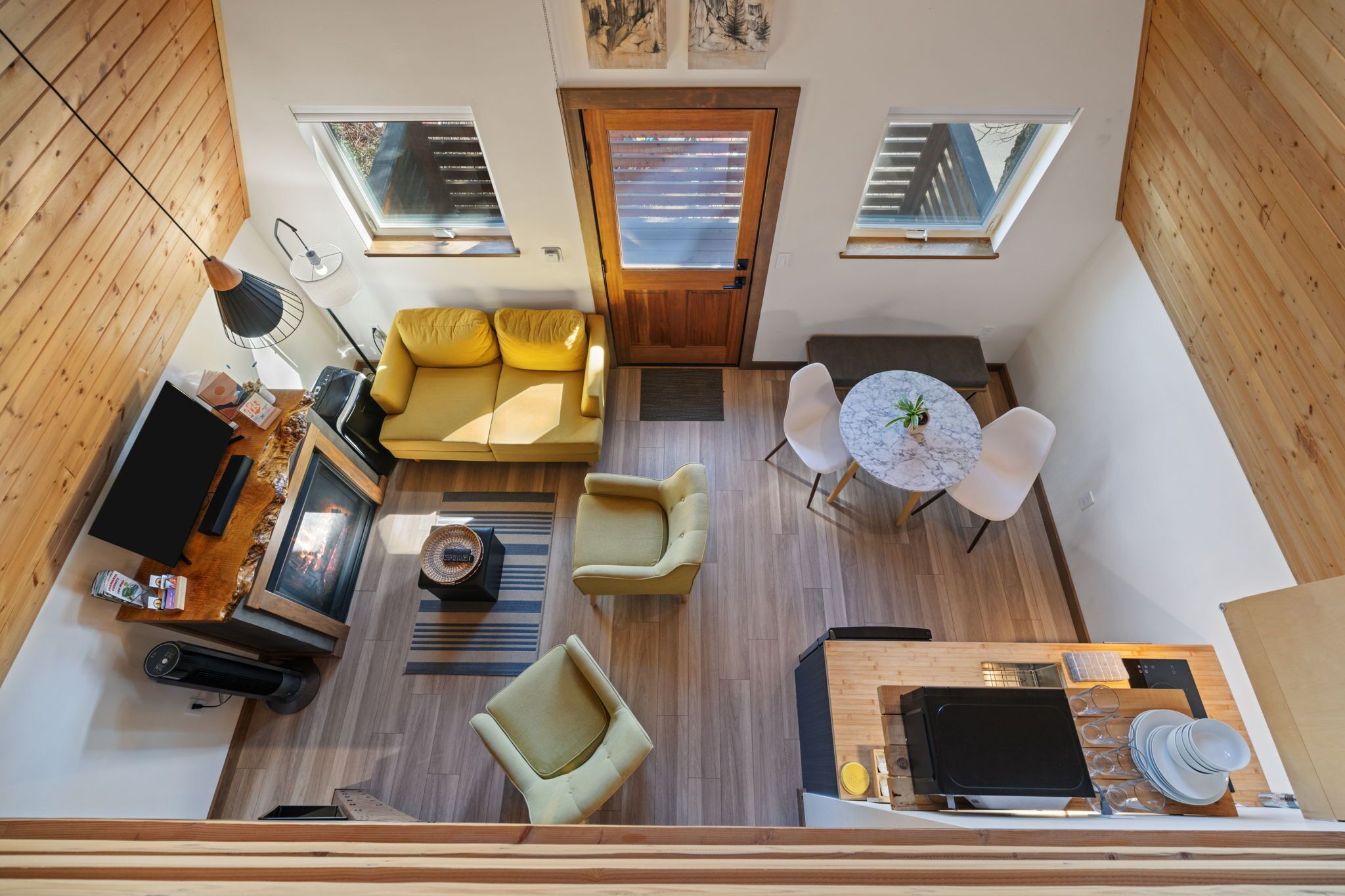 A compact living space with a sofa, chairs, a dining table, a TV, and a kitchen area.
