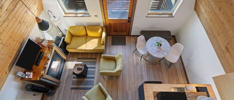 A compact living space with a sofa, chairs, a dining table, a TV, and a kitchen area.