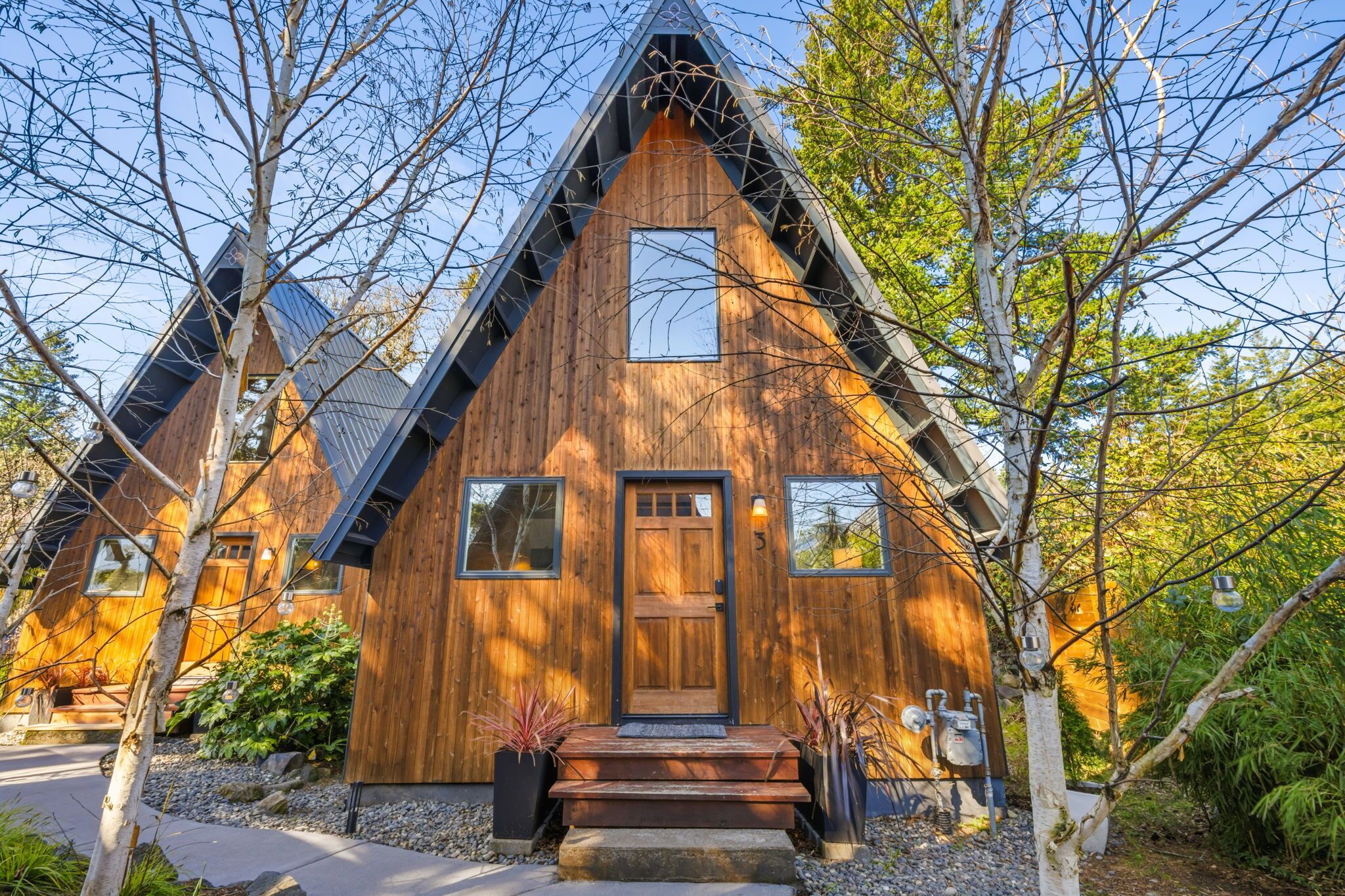 A wooden cabin with a triangular roof, a front door, and windows.