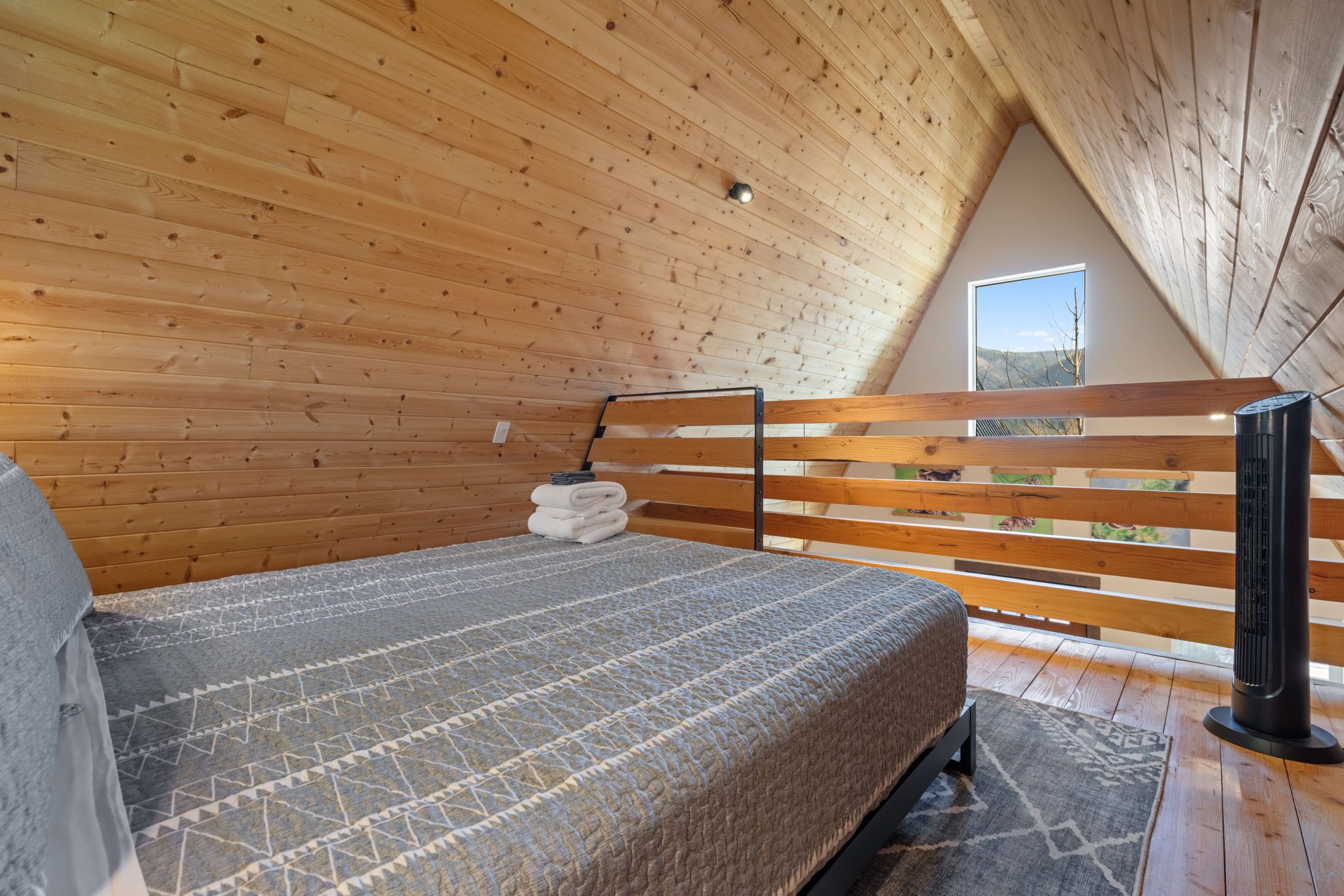 A wooden-paneled room with a bed, a heater, and a window with a view.