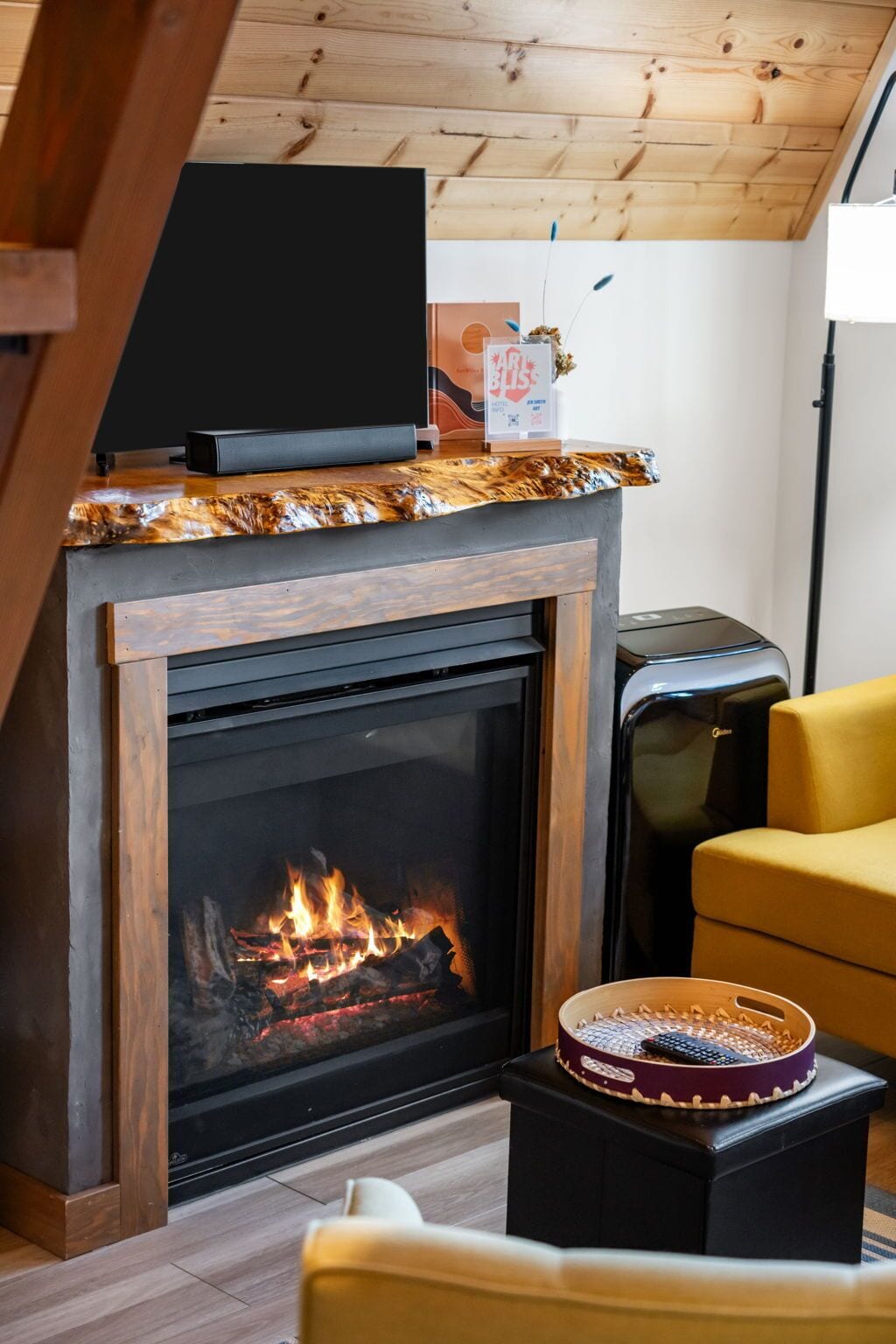 A modern living room with a fireplace, a flat-screen TV, and a yellow sofa.