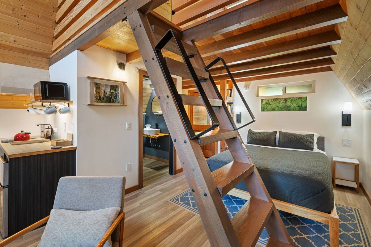 Un interior moderno con cama estilo loft, una zona de cocina con microondas y un espacio para comer.