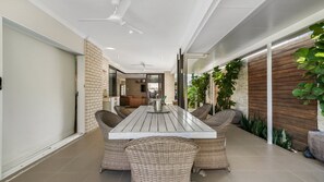 A modern dining area with a long table, wicker chairs, and a brick wall. - The Cabana Oasis, TOP NOTCH (WOORIM)