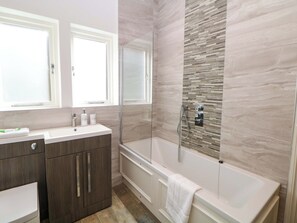 Ein Badezimmer mit Waschtisch, Badewanne und Duschbereich.