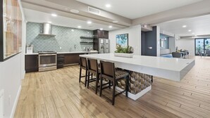A modern kitchen with a large island, wooden flooring, and built-in appliances. - The Cays at Ocotillo | Luxury Condo | Resort Pool (Chandler)