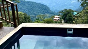 Une piscine aux eaux cristallines, dotée d’une terrasse en bois et offrant une vue sur un paysage montagneux.