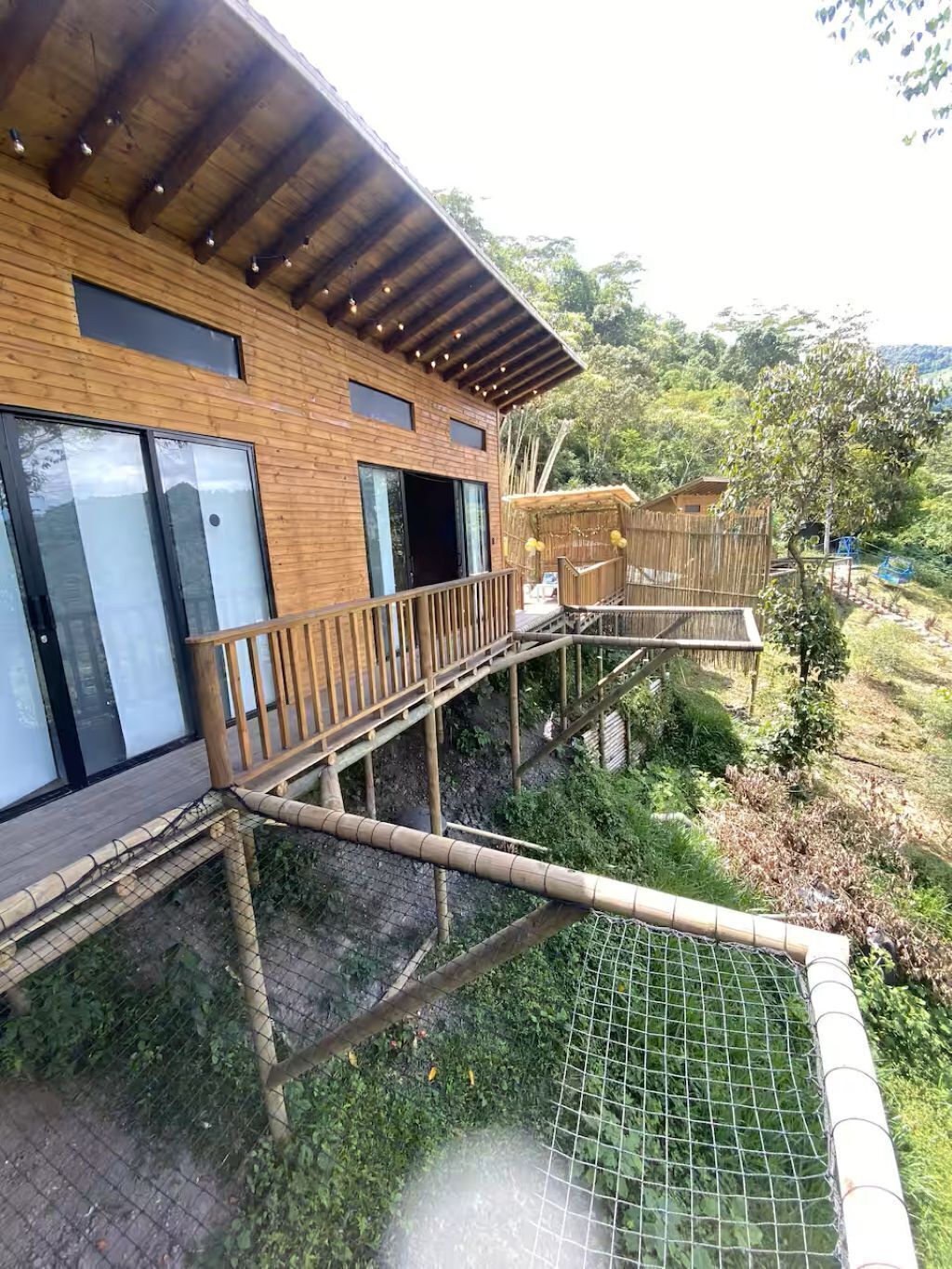 A wooden building with large windows, a balcony, and a netted area.