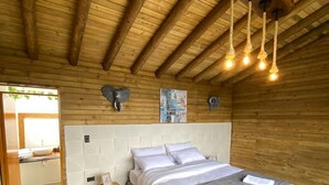 Une chambre à coucher aux murs lambrés, avec un lit, une table de chevet et un luminaire suspendu.