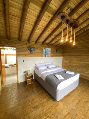A wooden-paneled bedroom with a bed, bedside table, and a hanging light fixture.