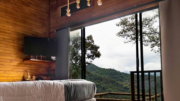 Une chambre avec un lit, une télévision et un balcon offrant une vue sur la montagne.