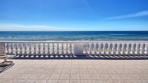 Un balcon avec vue sur la mer, un sol carrelé et une balustrade blanche.