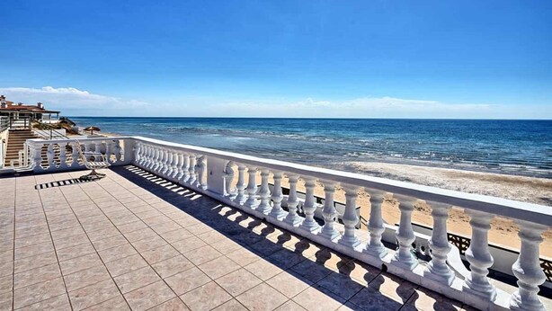 Un balcon donnant sur la mer, avec un sol carrelé et une balustrade blanche.